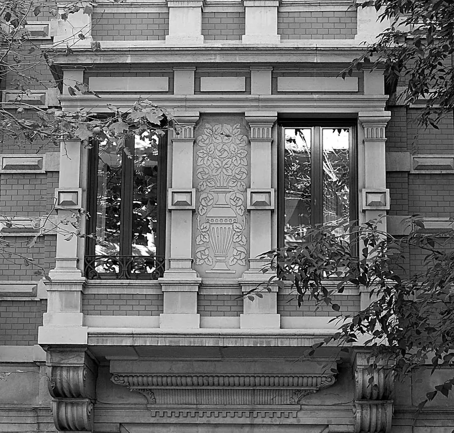 Ventana modernista con relieves de piedra en una fachada del Eixample